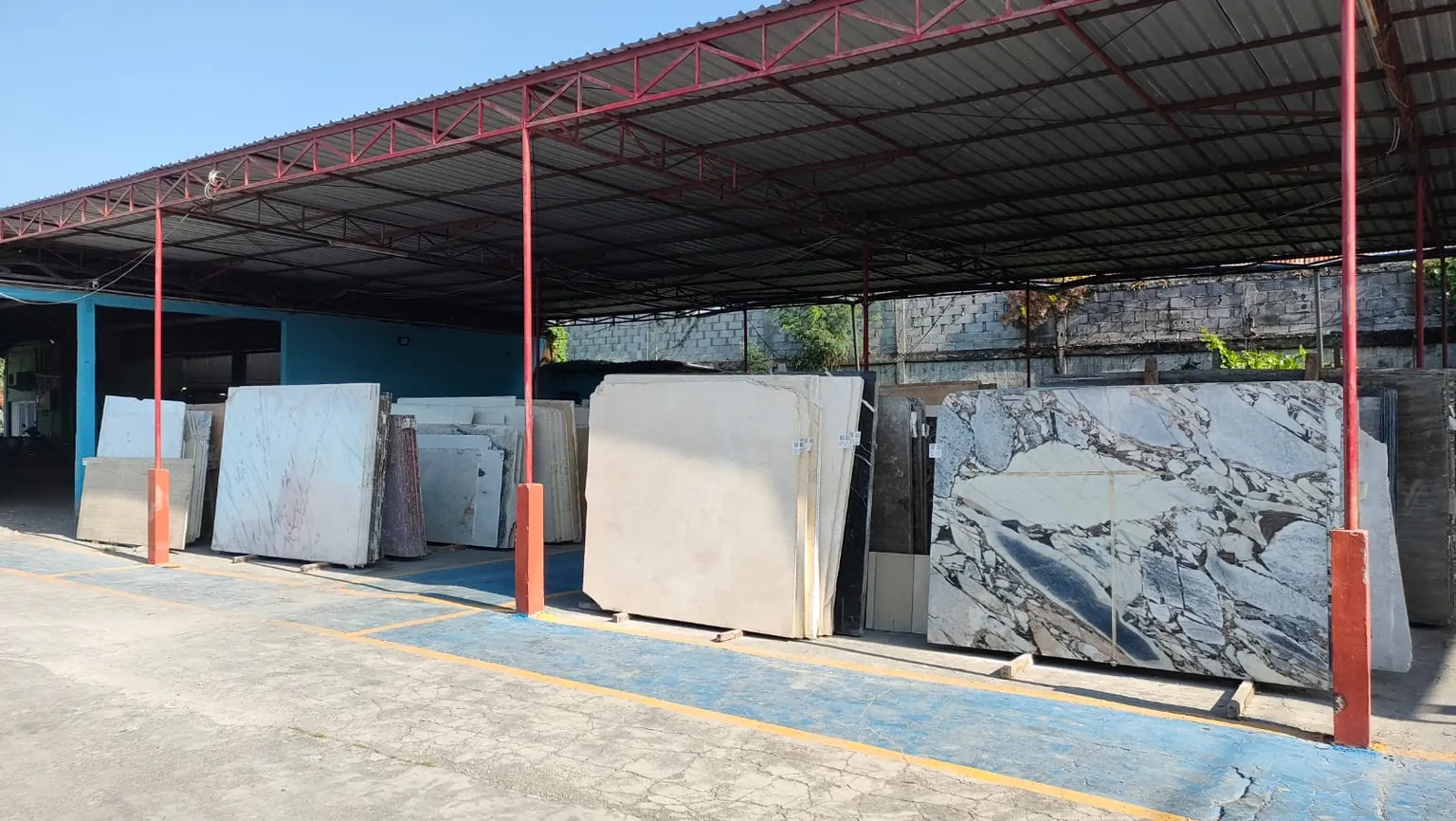 Marble and granite slabs standing under the canopy of the Brescia Stone Bali yard in Denpasar